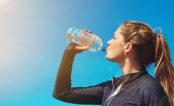 Shot of a sporty young woman drinking water outdoors