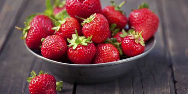 Strawberries in a bowl on rustic wood